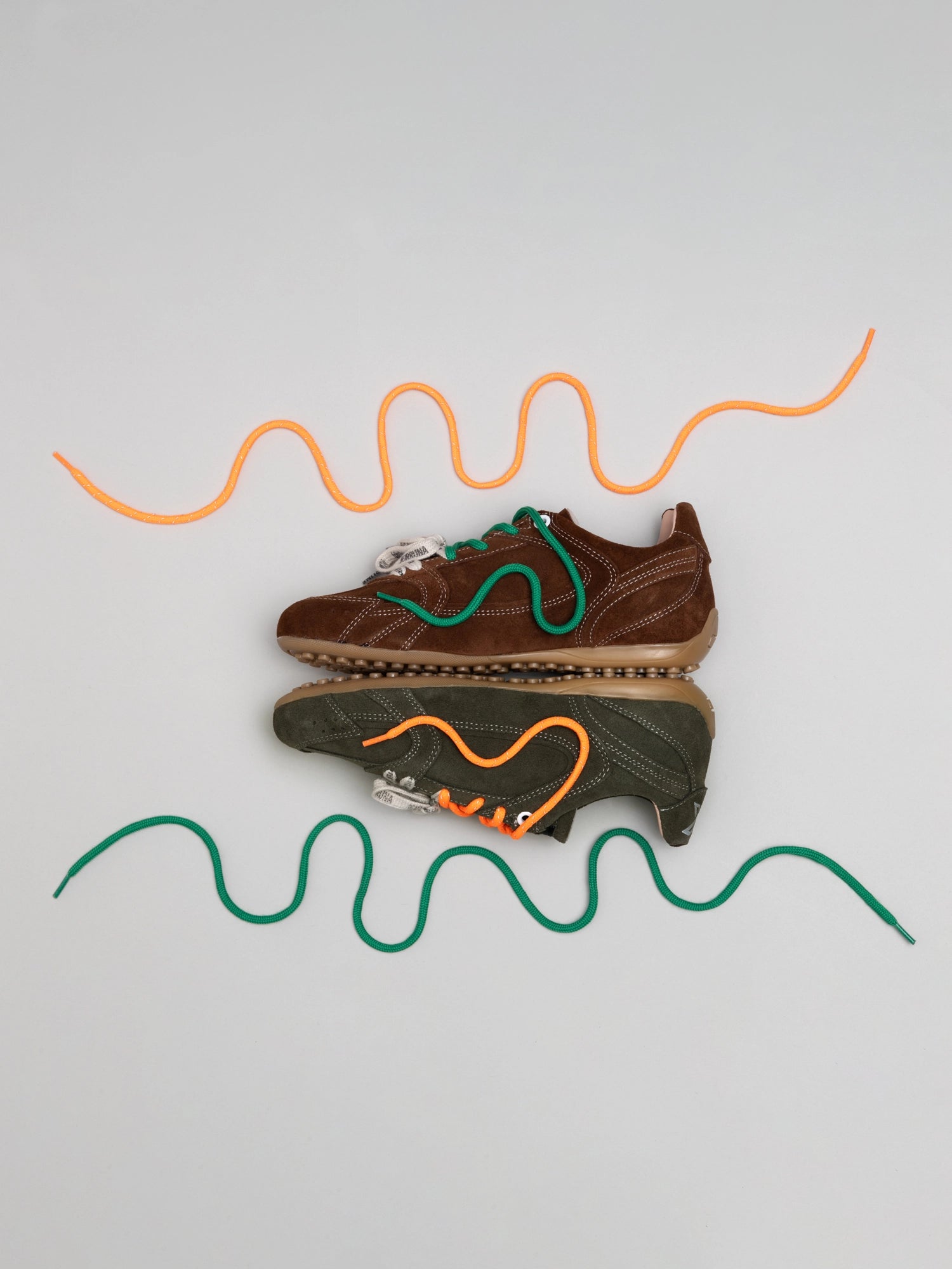 Two pairs of shoes with colorful shoelaces on a light gray background